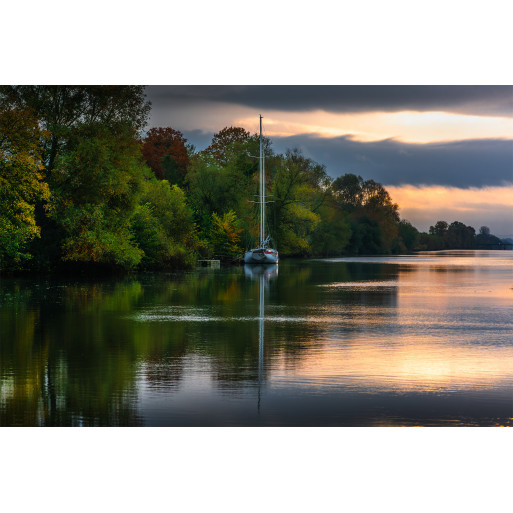 Sailboat and its reflection at sunrise